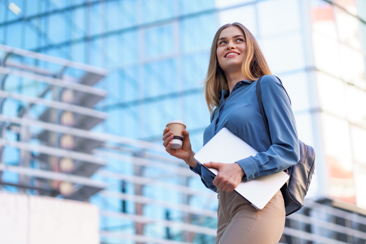 Portrait smiling woman holding laptop and coffee outdoors